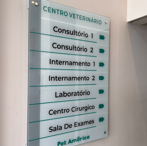 Placa de vidro na entrada listando os setores: consultórios 1 e 2, internamentos 1 e 2, laboratório, centro cirúrgico e sala de exames